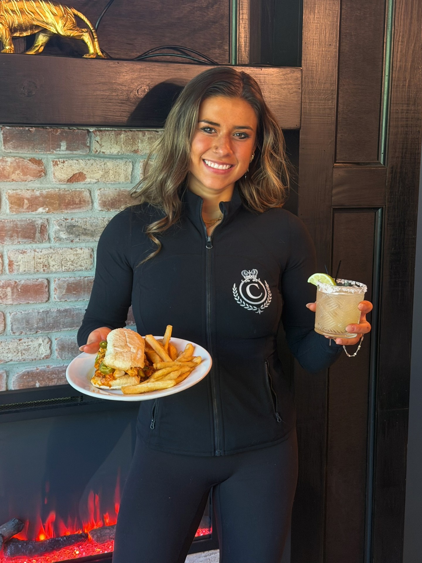 Server with a margarita and burger by the fireplace
